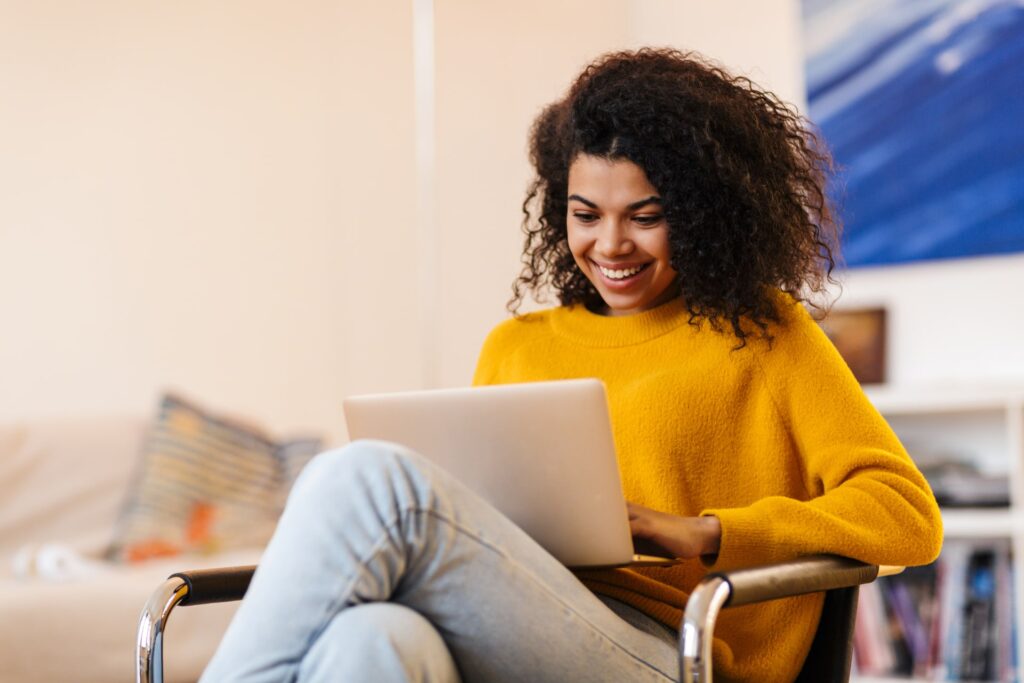 Image of cheerful african american woman using laptop